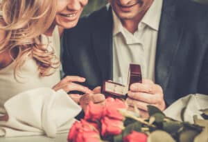 couple getting engaged and looking at a ring in a box